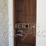 Puerta de entrada realizada en madera maciza ( pino/ iroko) con tablas engargoladas, cristal climalit y verja. A medida